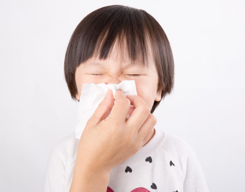 A young child having help blowing his nose.