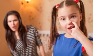 A young girl picking her nose with her mother in the background looking grossed out