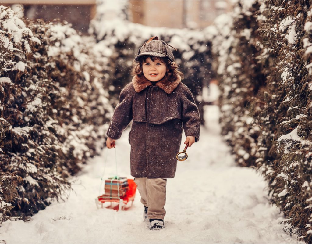 Toddler walking in the snow with a magnifying glass