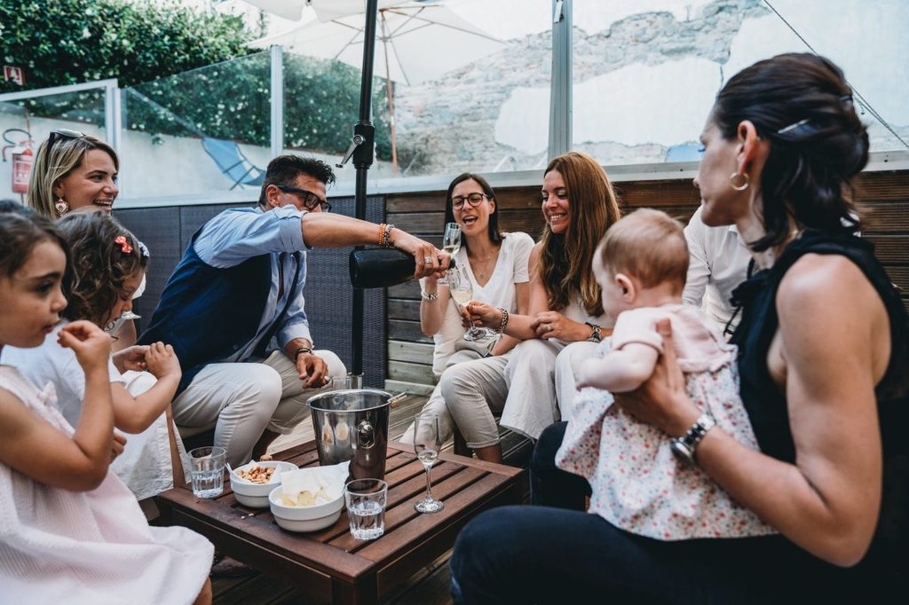Friends are celebrating together with a bottle of champagne and kids are around