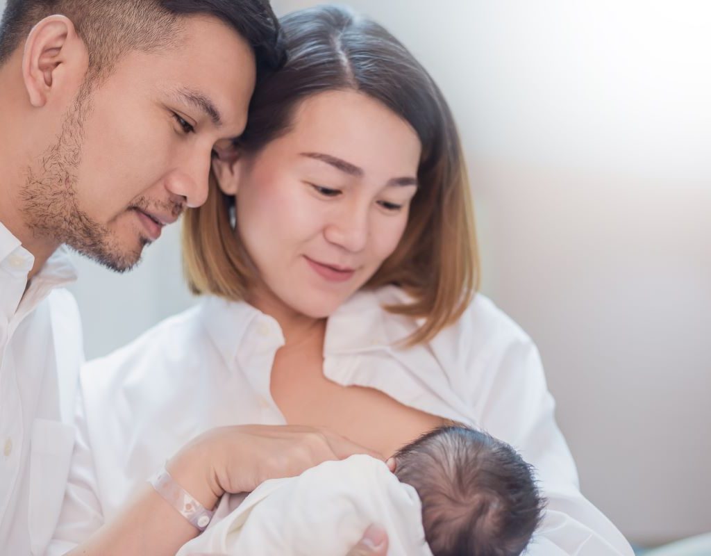 Mom breastfeeds baby and Dad watches.