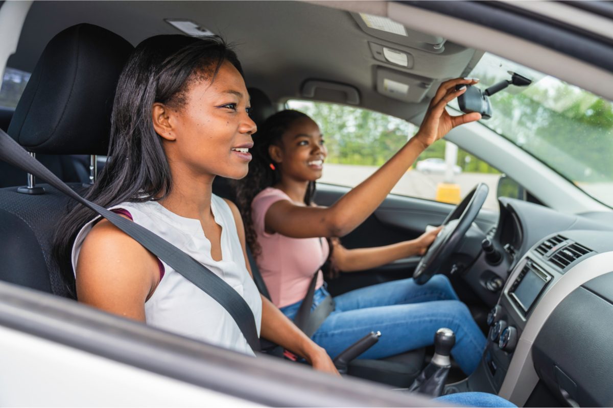 A teen driving a car with their parent in the passenger seat