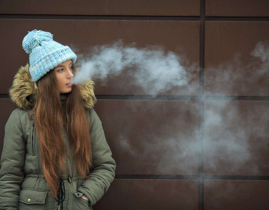 A teen blowing vape smoke out