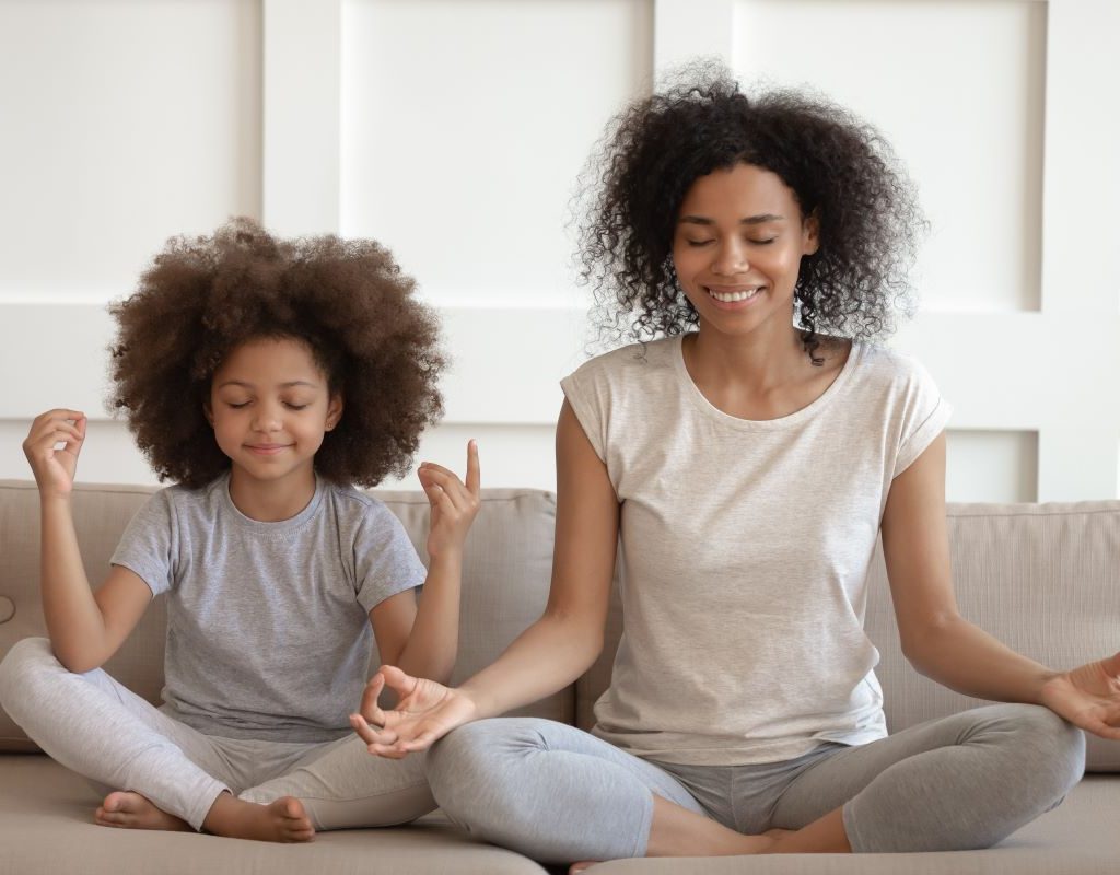 Mom and daughter sitting on couch meditating