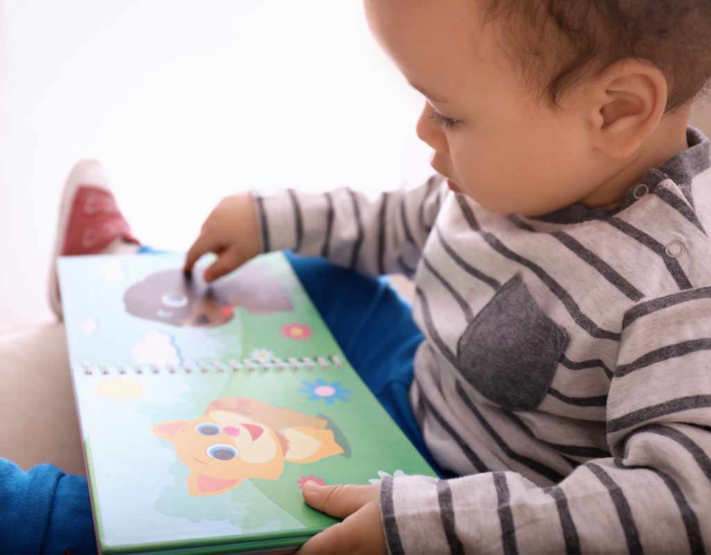 happy toddler boy reading a picture book