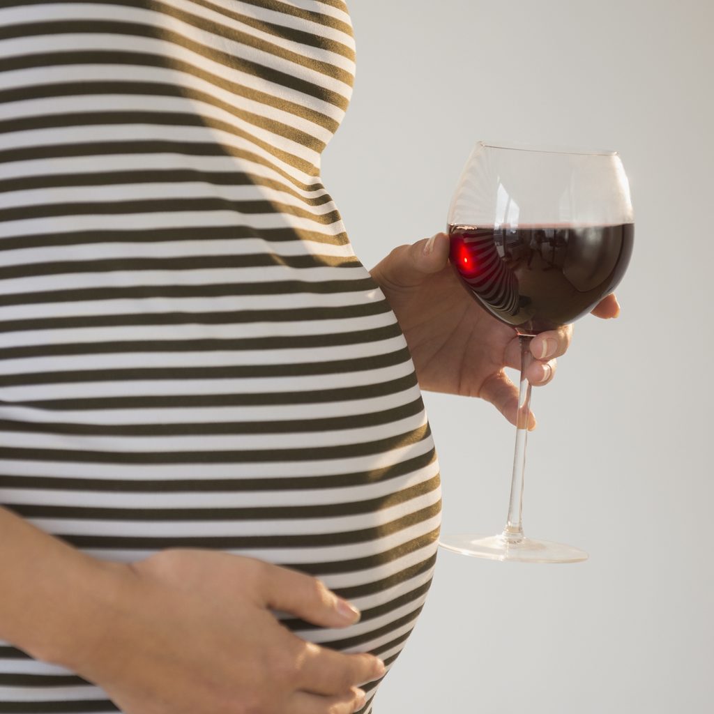 Pregnant woman holding glass of red wine