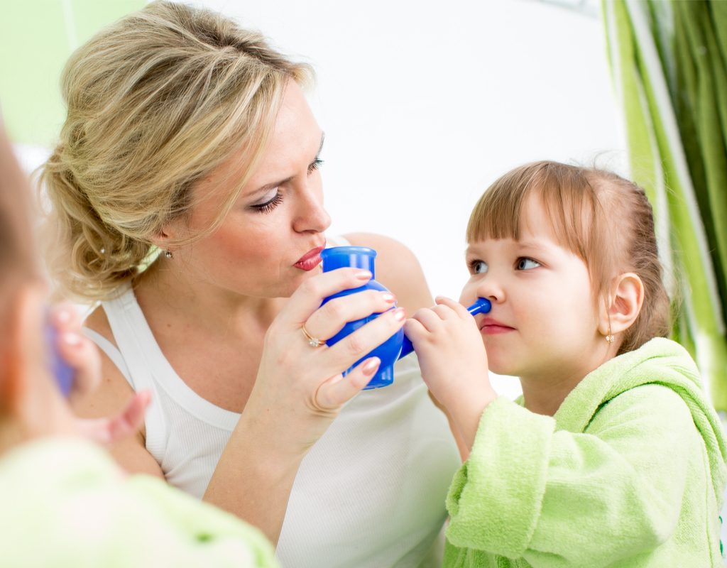 mom helping little girl use a neti pot to help ease allergy symptoms