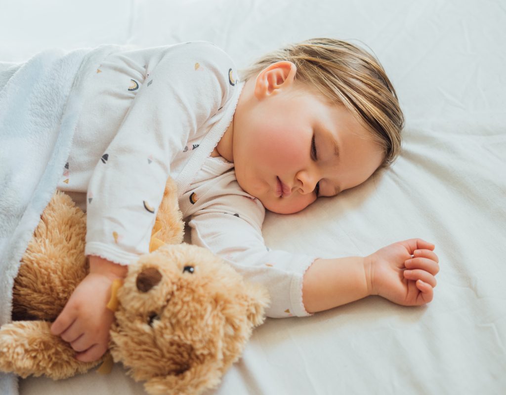 Sleeping toddler with their teddy bear.