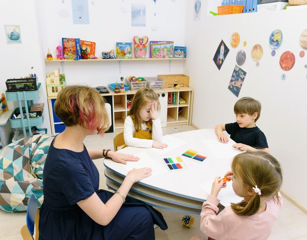 Teacher sitting at a table with preschool students