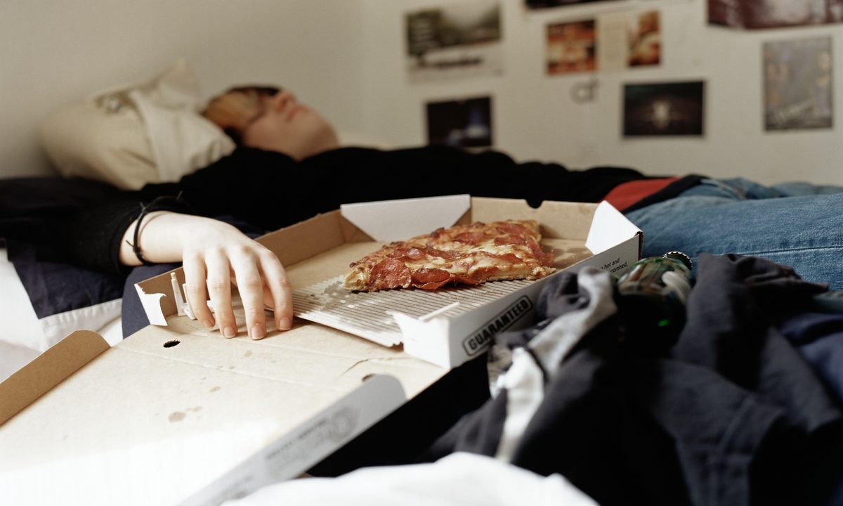 Teen sleeping with pizza on bed