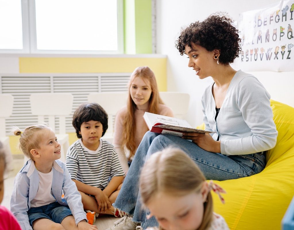 Kindergarten teachers reading a story to the class