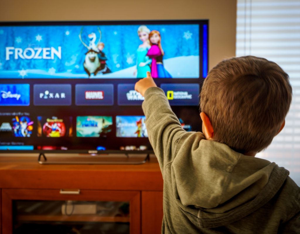 A boy pointing to which Disney movie he wants to watch