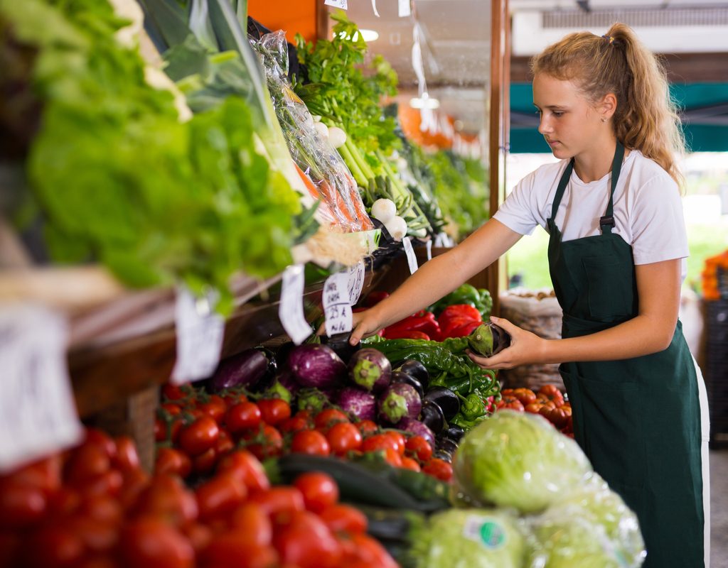 A teenager working at a grocery store stocking the shelves