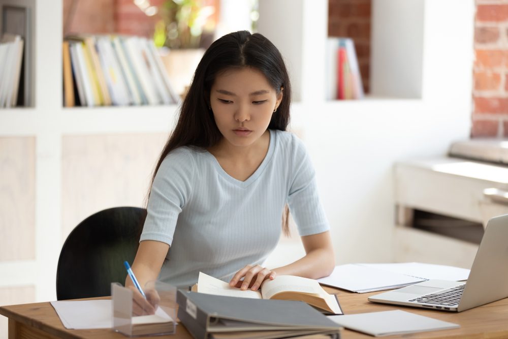 Teenager taking notes from a book to study
