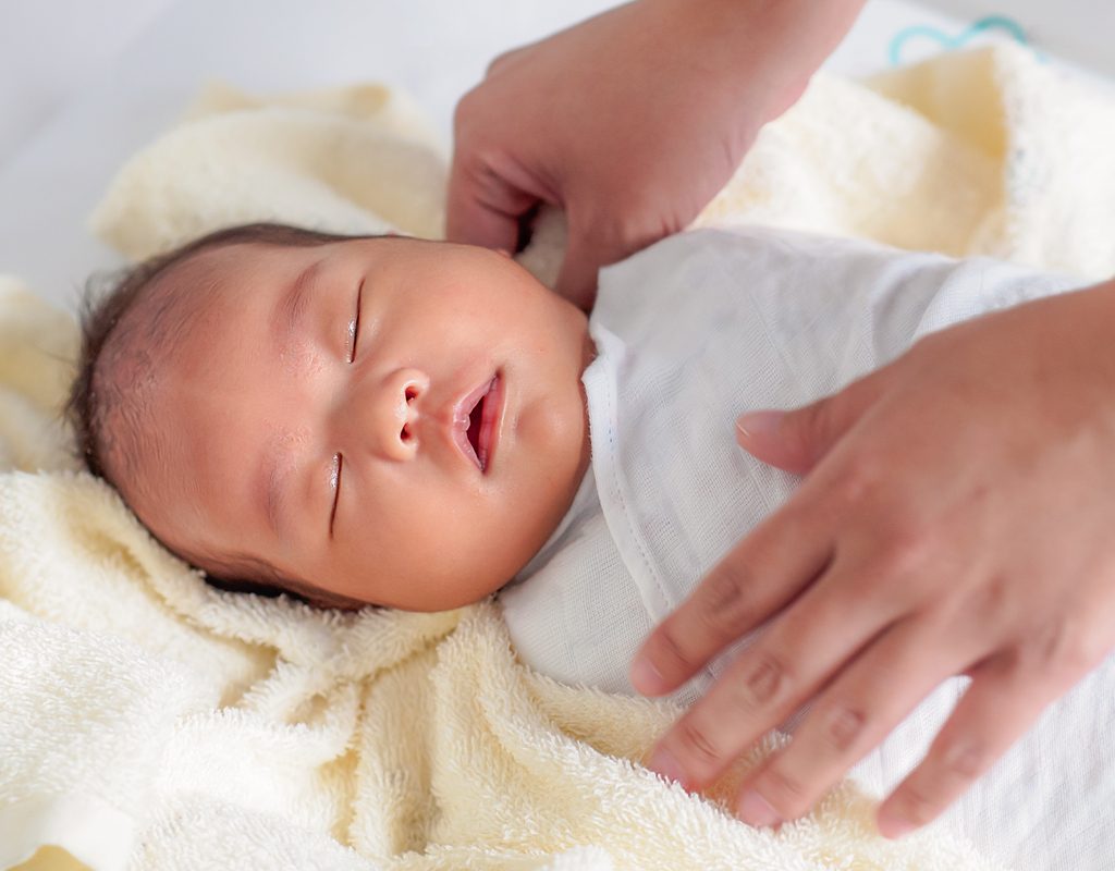 A sleeping baby being swaddled