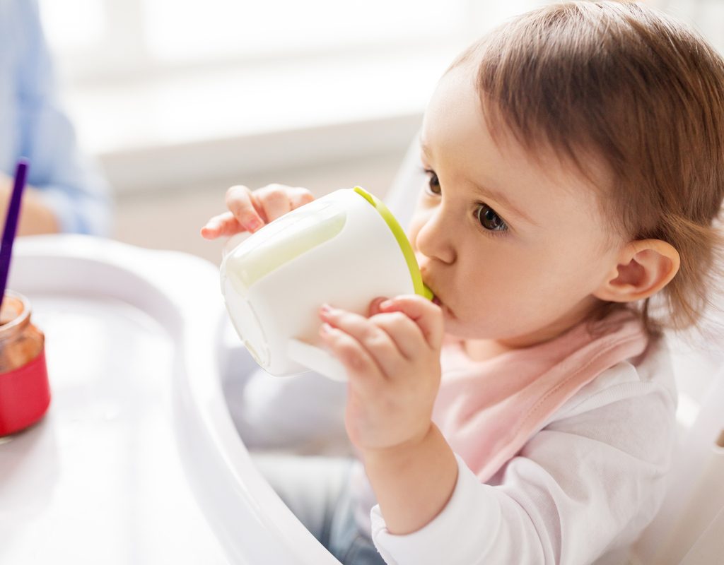 A young child drinking out of a sippy up.