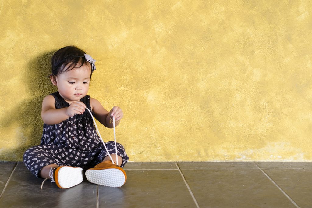 A little girl playing with her shoe strings.