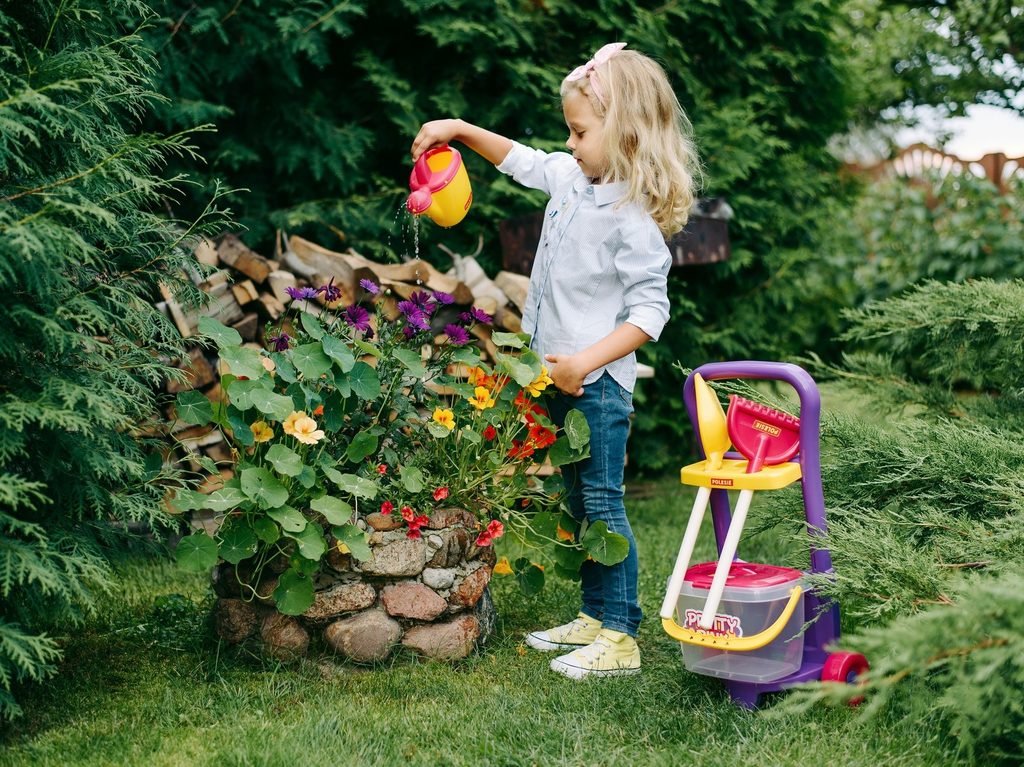 Young girl watering plants with toy.