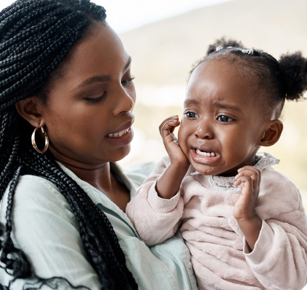 A mother holding her crying toddler.