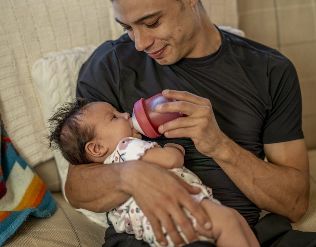 A parent bottle feeding a little baby.