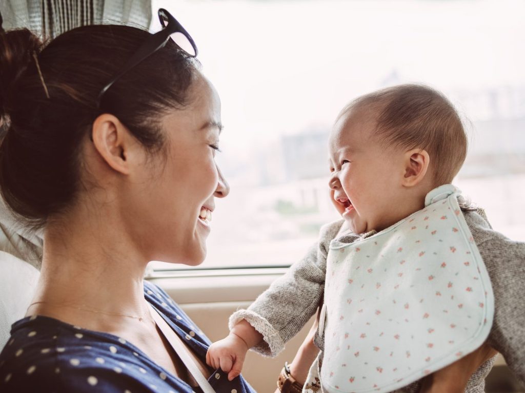 A mother holding her baby that is wearing a bib.