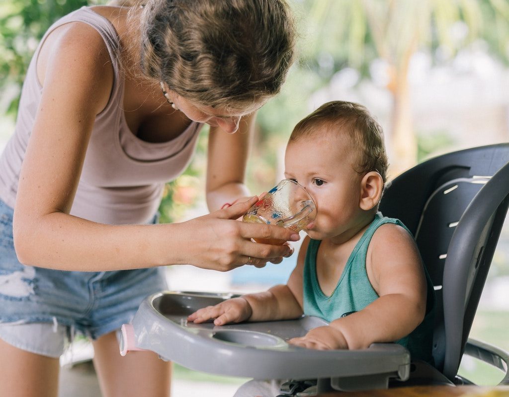 Mom holding a cup while baby drinks from it