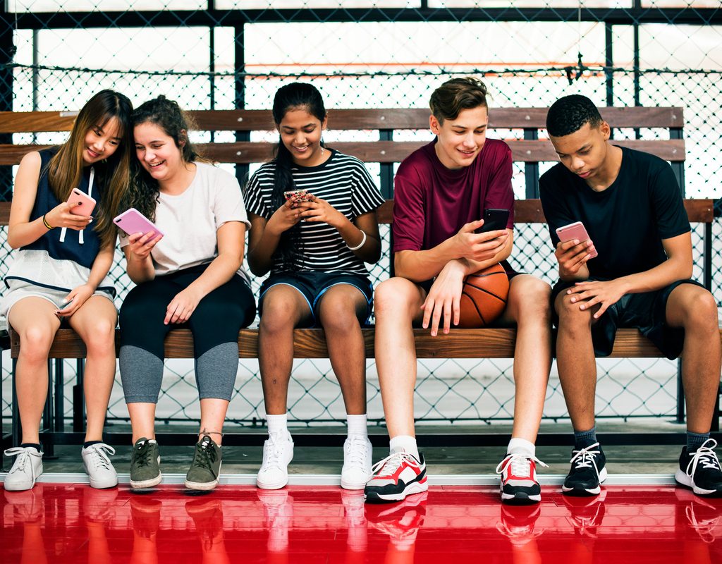 A group of teens looking at their phones.