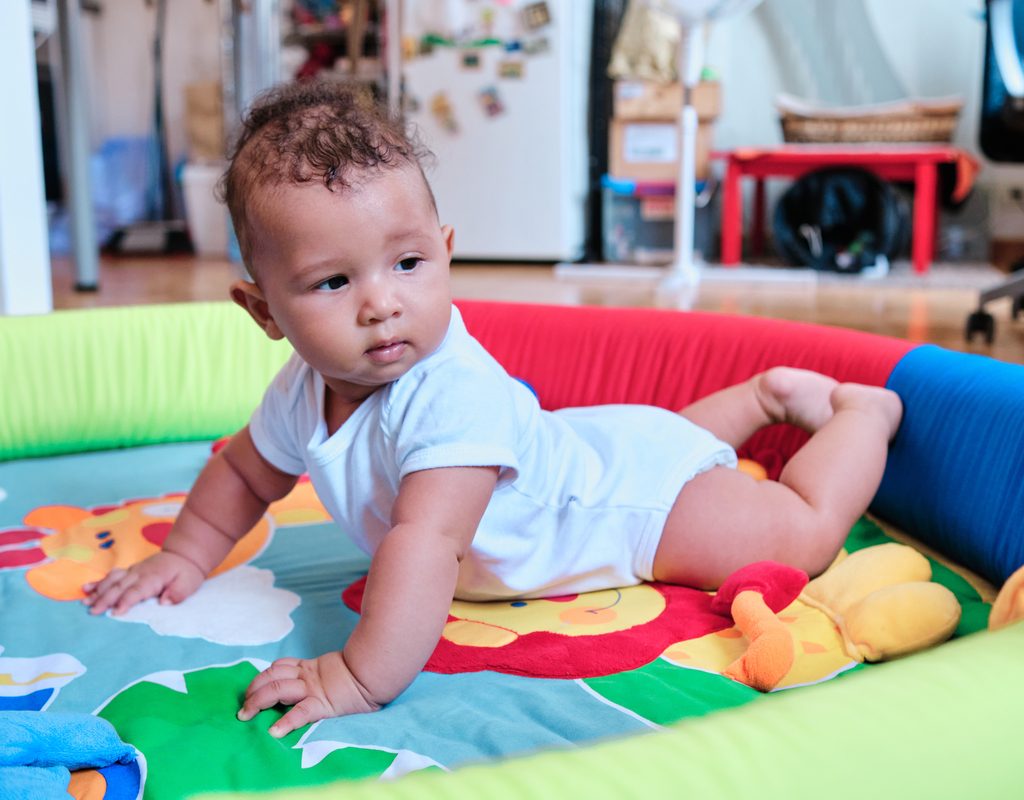 A little baby on their stomach on a play mat