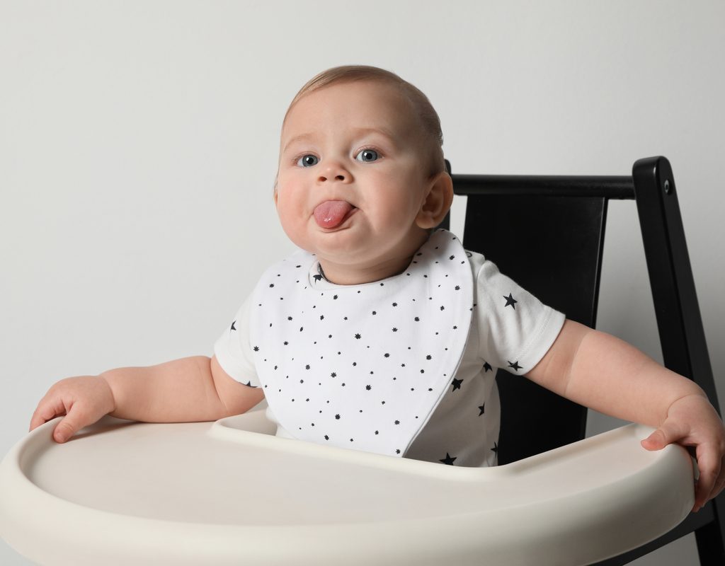 A baby sticking out their tongue and wearing a bib.