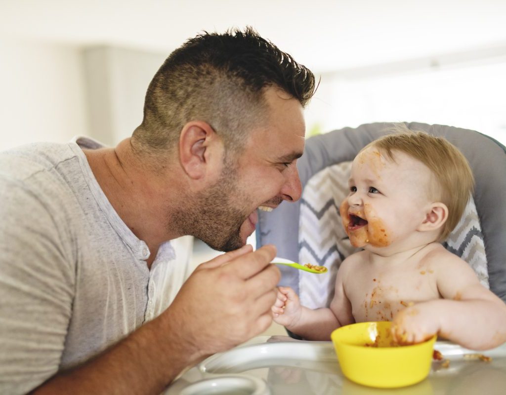 A parent feeding their baby some baby food.