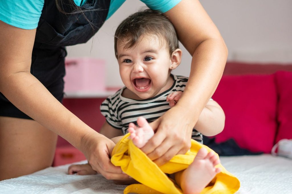 A baby getting dressed with the help of a parent.