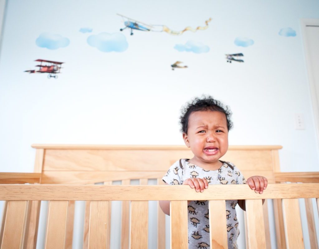 A toddler waking up crying in their crib