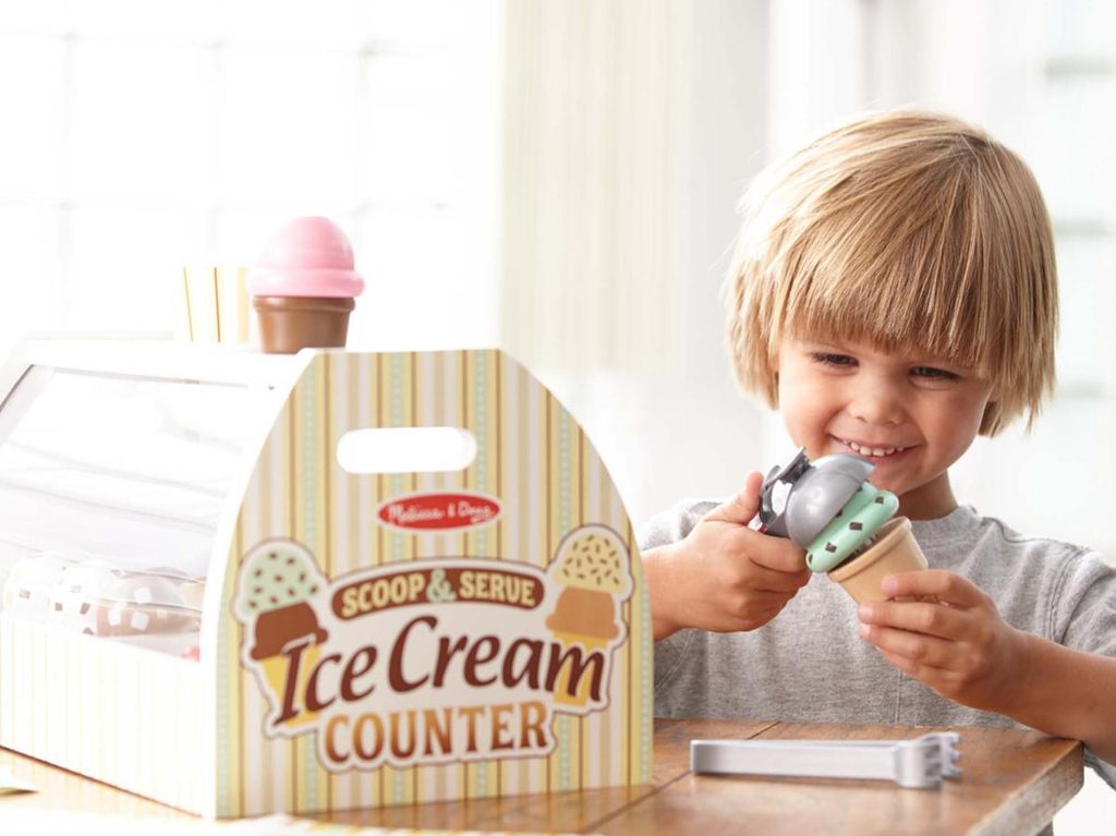 A boy playing with the Melissa & Doug Scoop and Serve Ice Cream Counter.