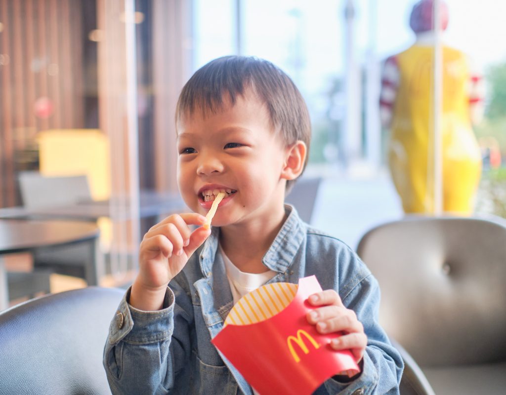 A young boy eating French fries