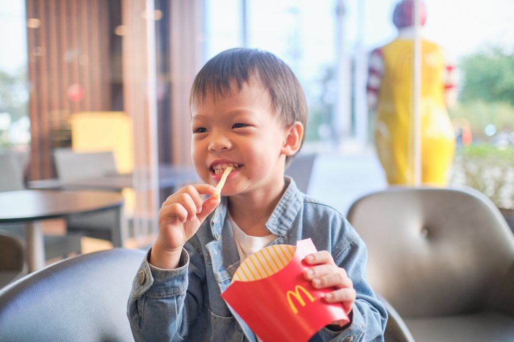A young boy eating French fries
