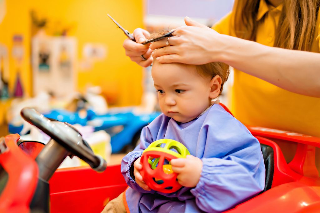 A child getting a haircut in a salon chair.