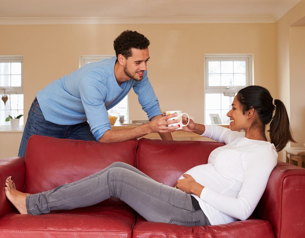 A man handing a pregnant person a hot drink