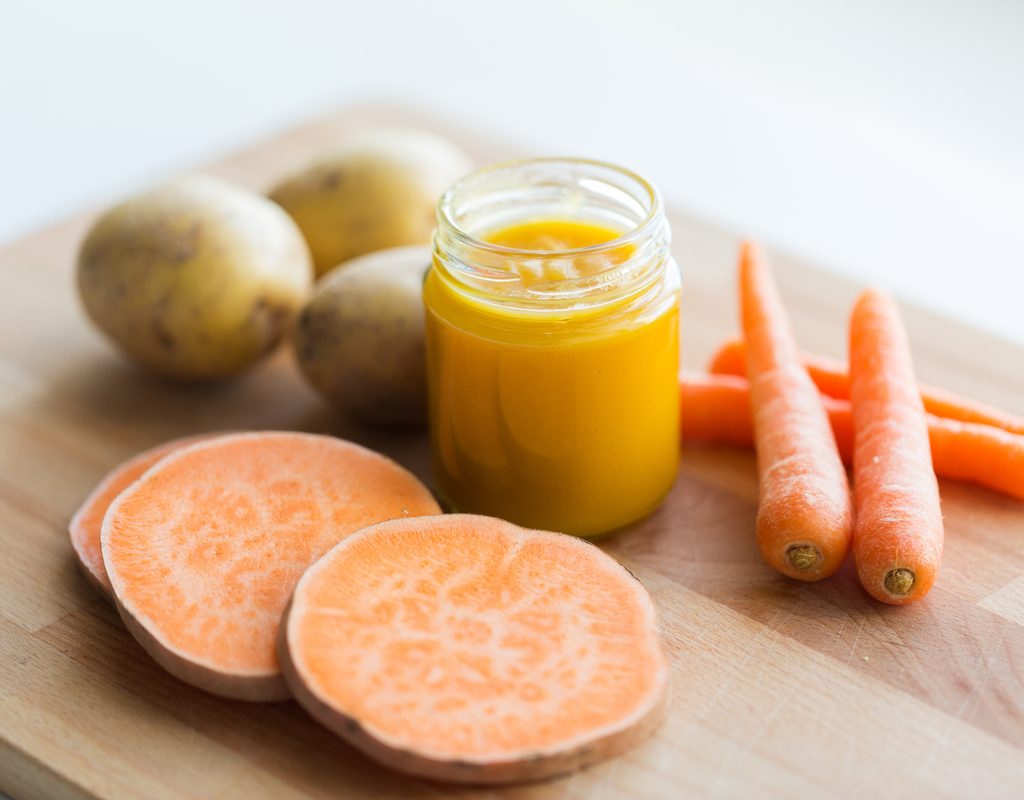 Sweet potatoes, carrots, regular potatoes, and baby food on a table.
