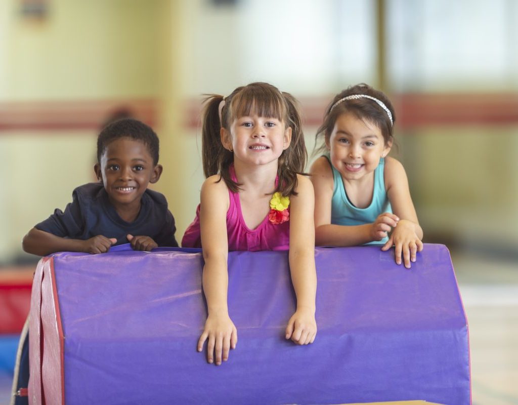 Three kids on a gymnastics mat.