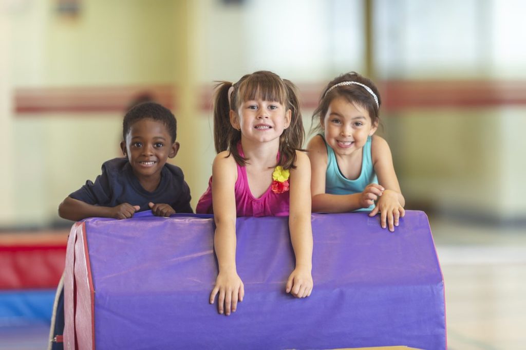Three kids on a gymnastics mat.