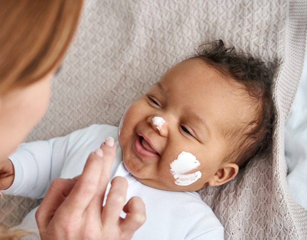 A parent putting sunscreen on a baby's face.