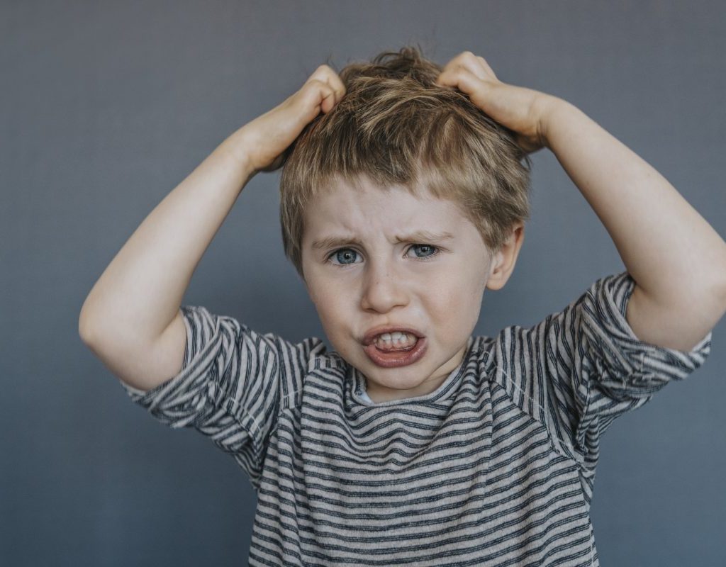 A little upset boy pulling at his hair.