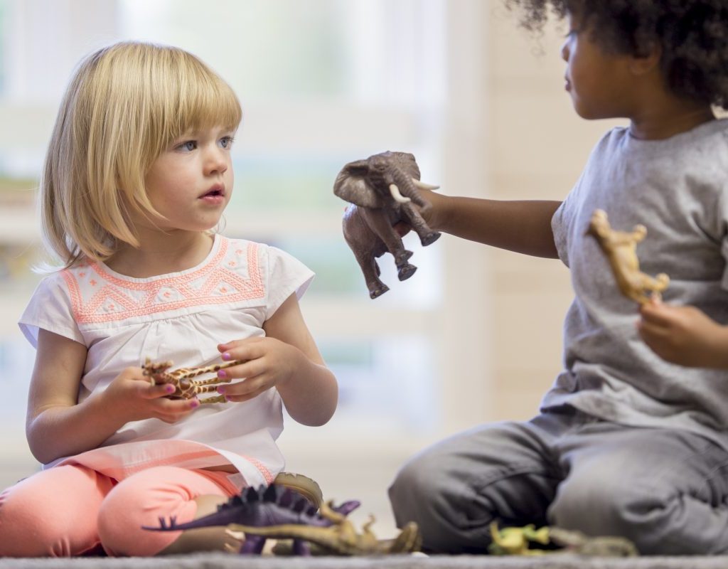 One toddler showing another a toy