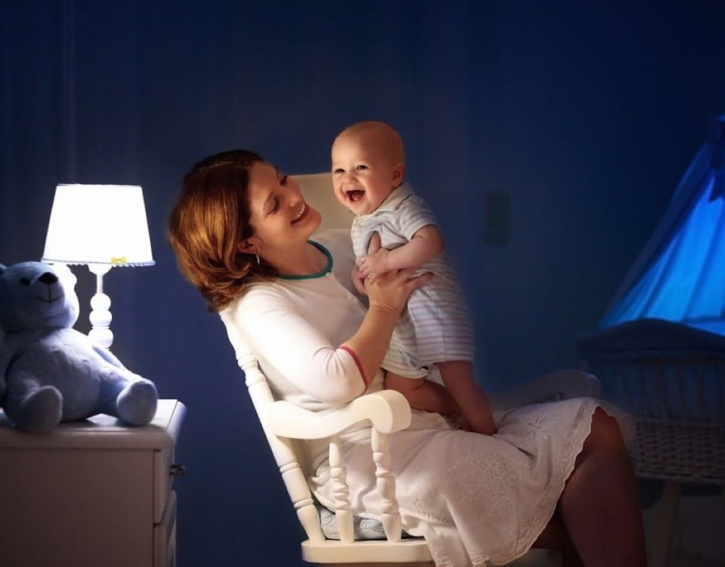 Mom sitting in rocking chair holding a smiling baby