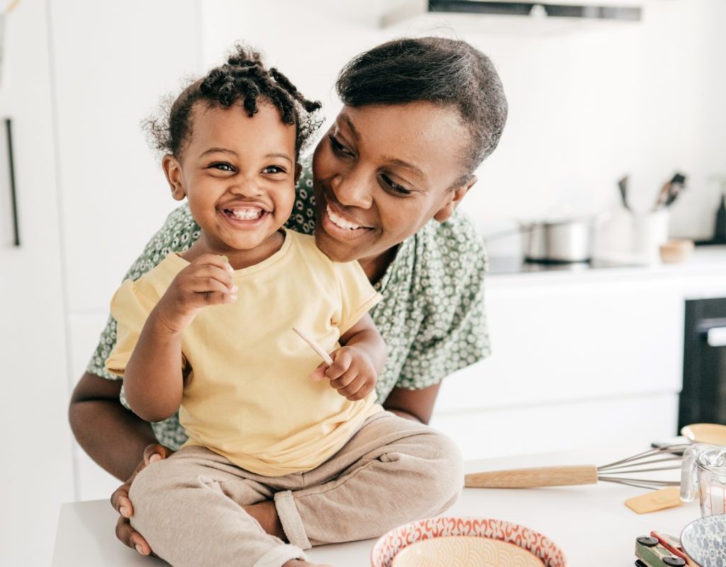 A toddler sitting on the counter while the parent hugs them
