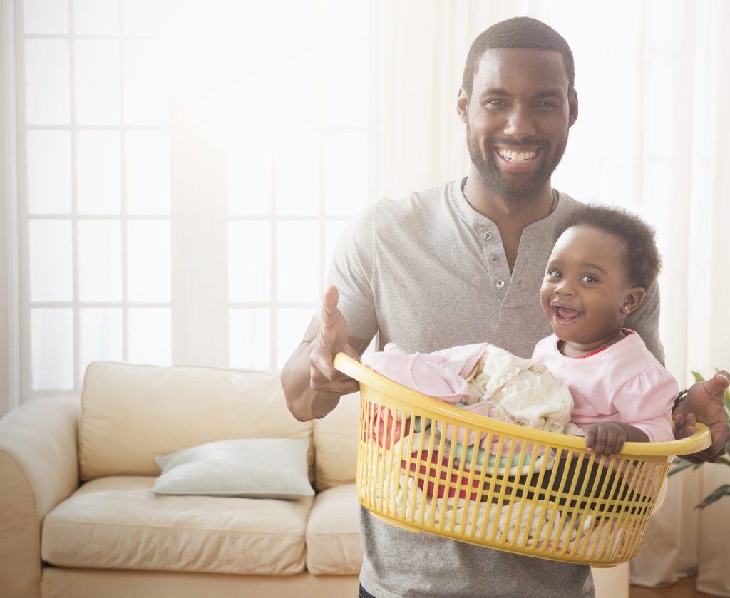 A father holding his baby in a laundry basket