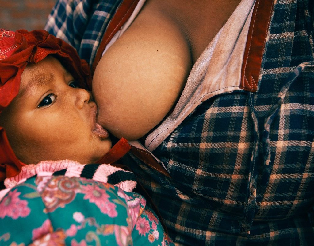 Baby girl with a dark red headlband breastfeeding