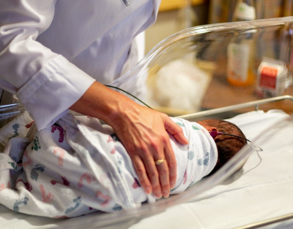 A doctor with a baby in a hospital bassinet
