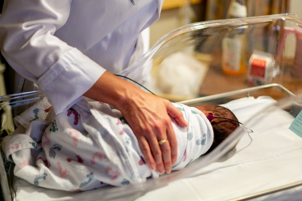 a doctor with a baby in a hospital bassinet