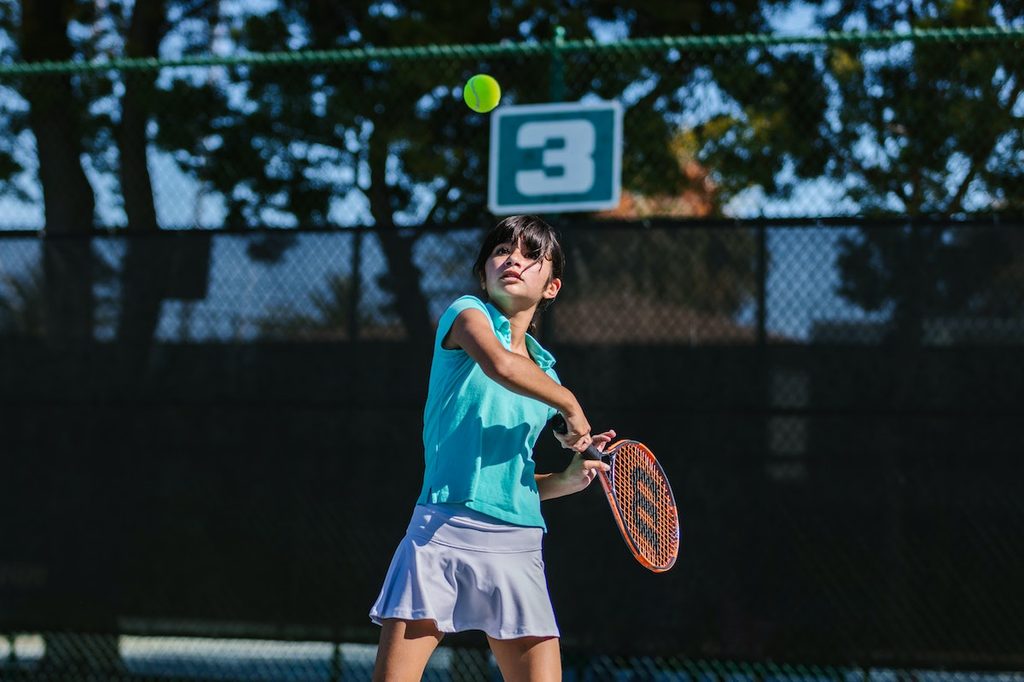 Teenage girl holding racket playing tennis